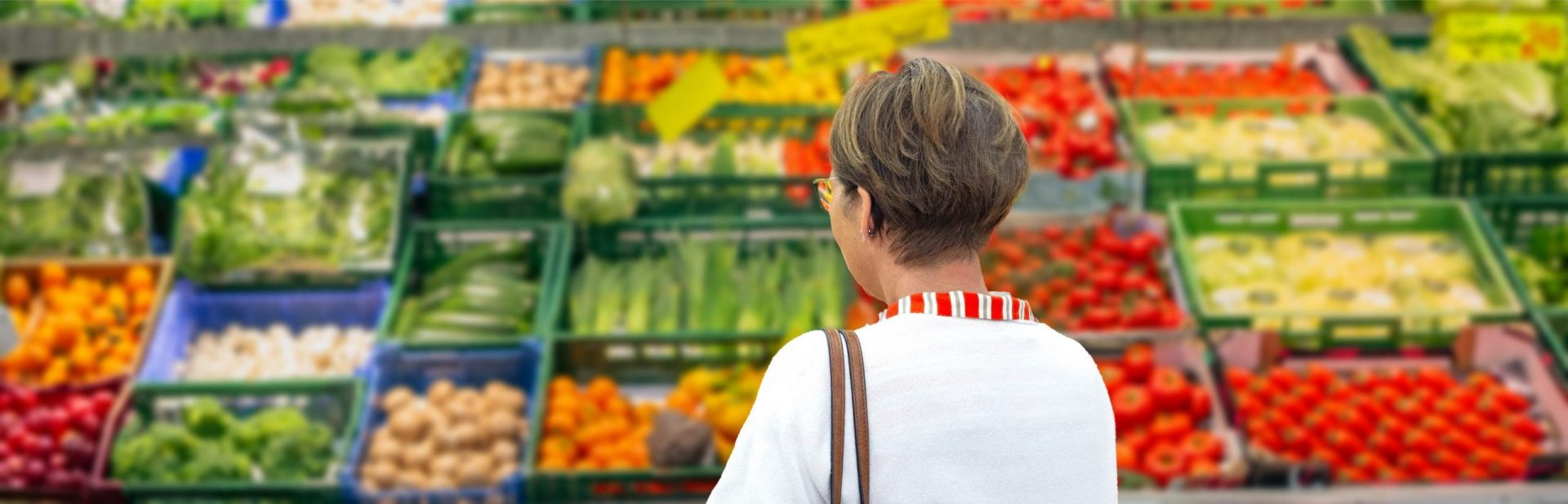 Frau von hinten vor einem Gemüseregal